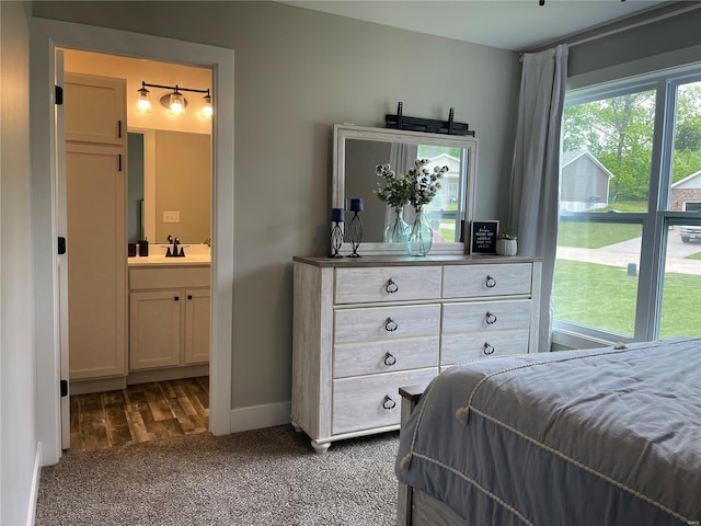 bedroom with ensuite bath, a sink, carpet floors, and baseboards