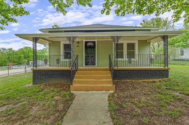 bungalow-style house featuring a front lawn, a porch, and fence