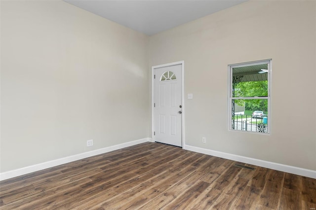 empty room with baseboards, dark wood-style flooring, and visible vents