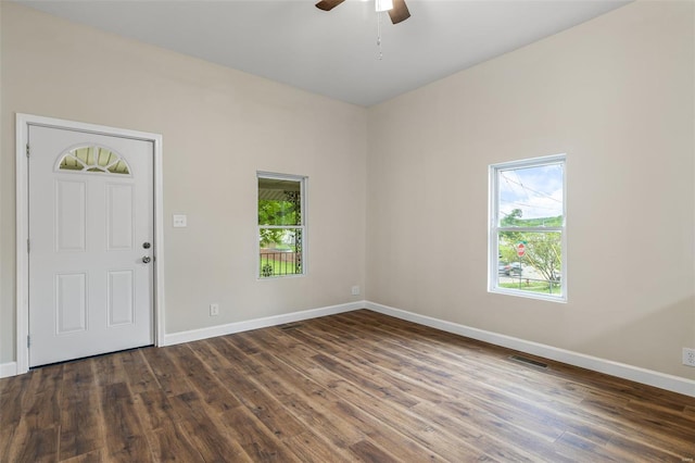 interior space with baseboards, dark wood-style floors, a ceiling fan, and visible vents