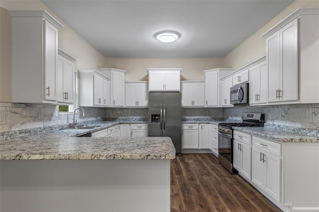 kitchen featuring a sink, a peninsula, backsplash, light stone countertops, and appliances with stainless steel finishes