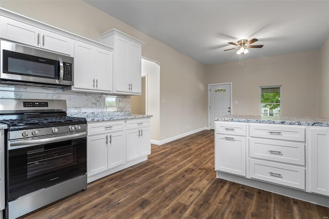 kitchen with a ceiling fan, baseboards, backsplash, appliances with stainless steel finishes, and dark wood-style floors
