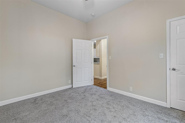 spare room with dark colored carpet and baseboards