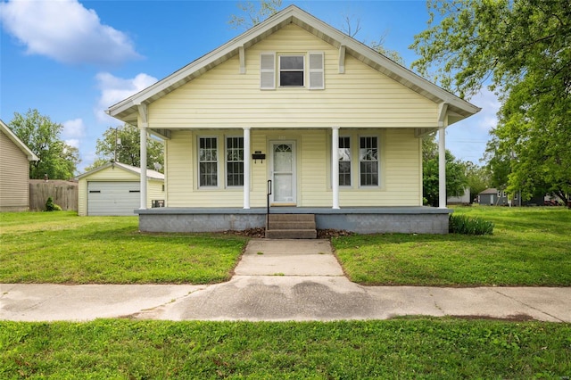 bungalow with a detached garage, a porch, and a front yard