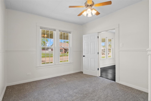 carpeted empty room with baseboards, ceiling fan, and a wealth of natural light