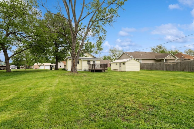 view of yard with fence, an outbuilding, a shed, and a wooden deck