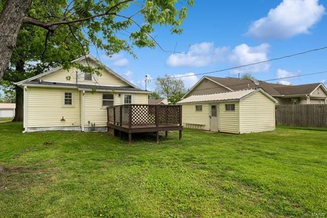 back of house featuring a lawn, fence, an outbuilding, and a deck