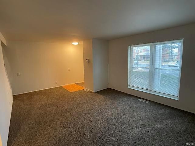 empty room featuring dark colored carpet and visible vents