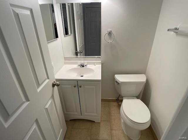 half bathroom featuring vanity, baseboards, tile patterned flooring, and toilet