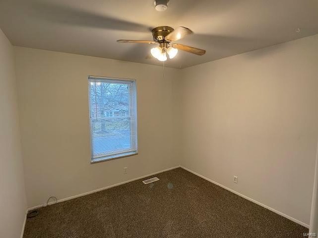 empty room featuring baseboards, ceiling fan, dark carpet, and visible vents