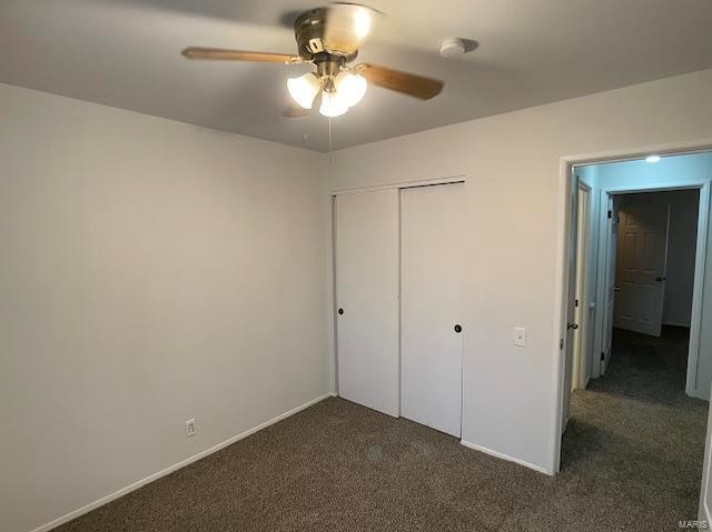 unfurnished bedroom with a closet, baseboards, a ceiling fan, and dark colored carpet