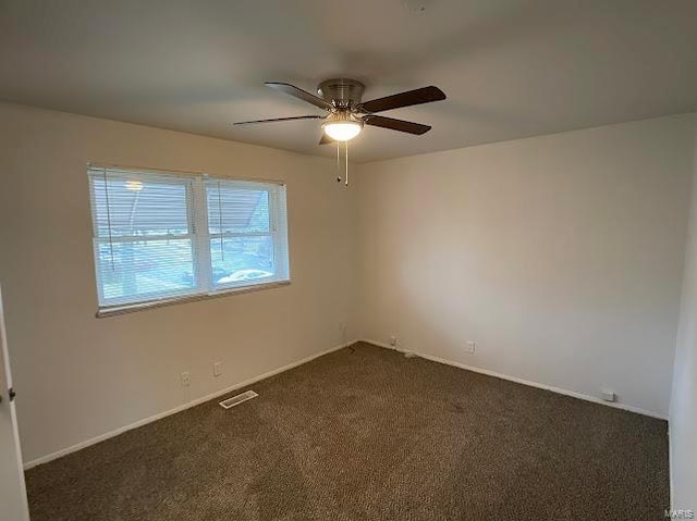 spare room featuring baseboards, ceiling fan, and dark carpet