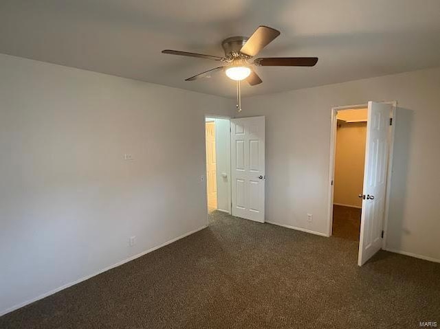 empty room featuring baseboards, ceiling fan, and dark colored carpet