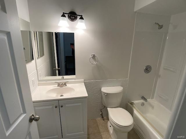bathroom featuring vanity, toilet, tile patterned floors, shower / bath combination, and tile walls