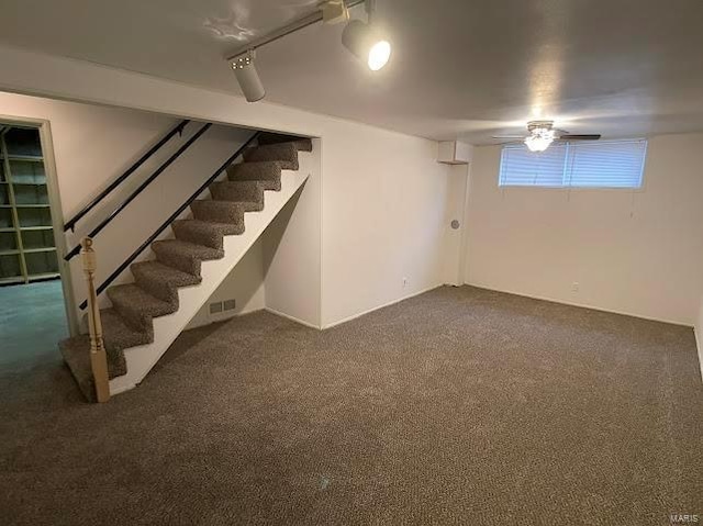 basement with visible vents, dark carpet, and stairway
