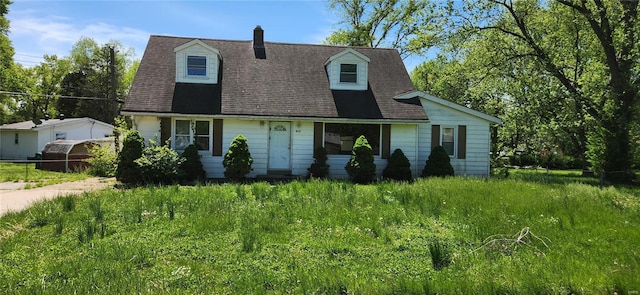 cape cod-style house featuring roof with shingles and a chimney