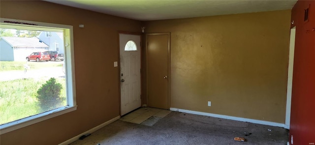 foyer entrance featuring baseboards, plenty of natural light, and light colored carpet
