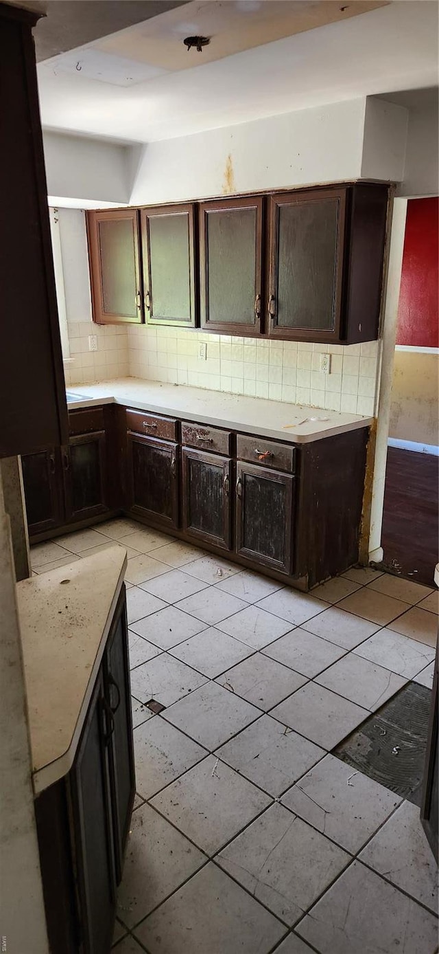 kitchen with light countertops, light tile patterned floors, dark brown cabinetry, and backsplash
