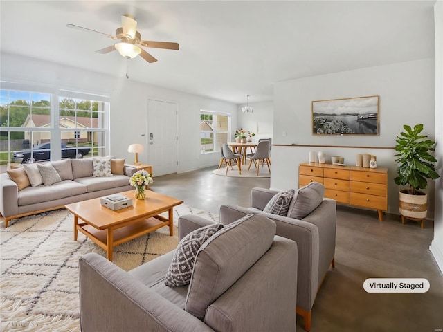 living area with ceiling fan, plenty of natural light, and concrete floors