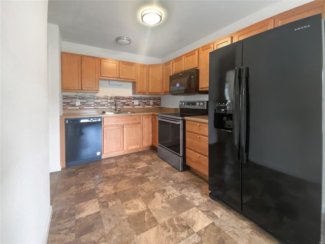 kitchen featuring a sink, stone finish floor, black appliances, light countertops, and tasteful backsplash