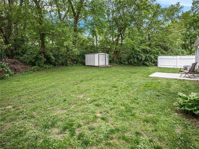 view of yard featuring fence, a storage shed, a patio, and an outbuilding