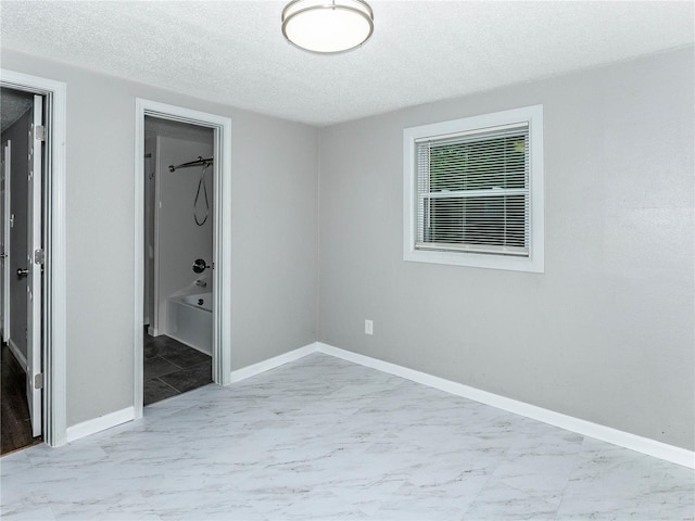 unfurnished bedroom with marble finish flooring, a textured ceiling, and baseboards
