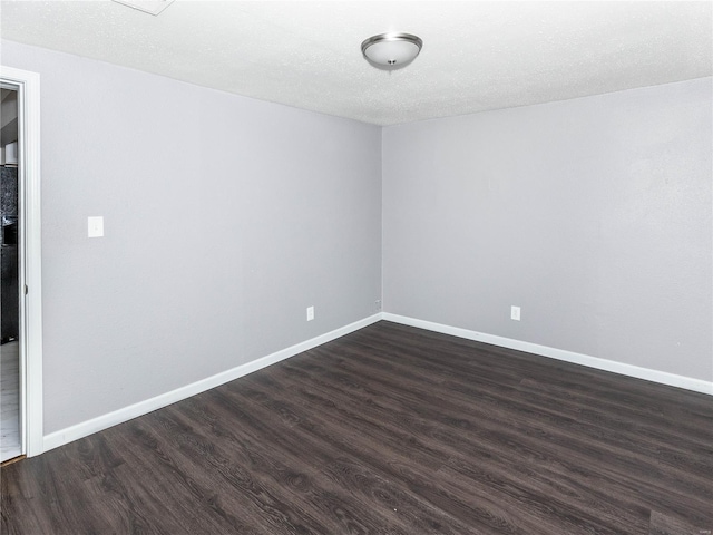 empty room with dark wood-style flooring and baseboards