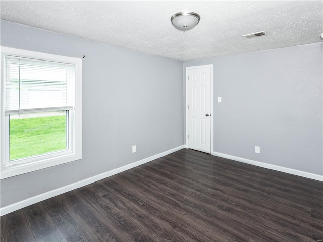 spare room with dark wood-type flooring, baseboards, and a textured ceiling