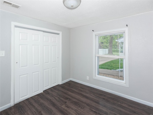 unfurnished bedroom with dark wood-style flooring, a closet, and baseboards