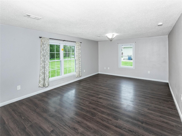 spare room with a textured ceiling, plenty of natural light, baseboards, and dark wood finished floors