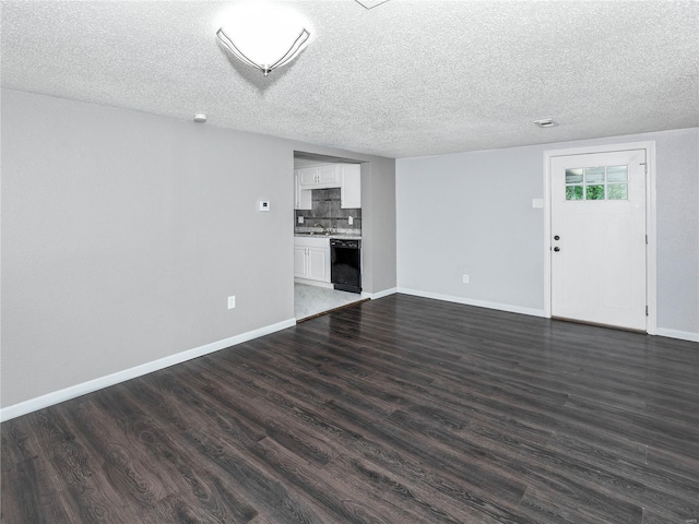 unfurnished living room with dark wood-style floors, baseboards, a textured ceiling, and a sink