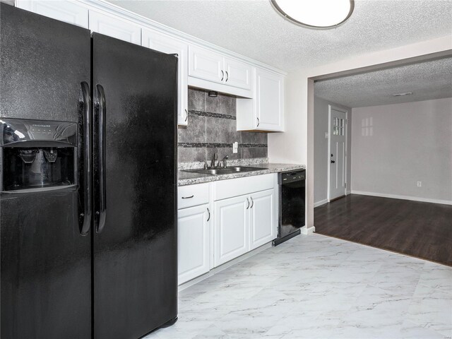 kitchen with black appliances, a sink, white cabinets, tasteful backsplash, and baseboards