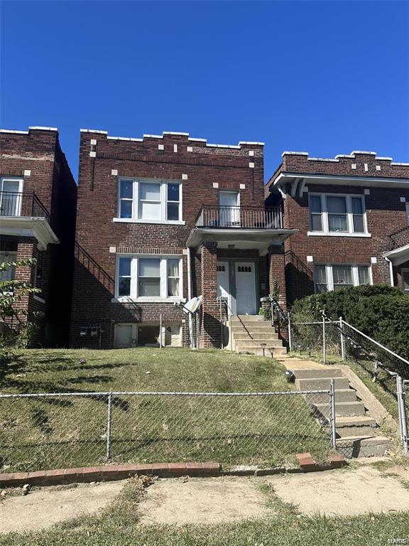 multi unit property featuring a balcony, brick siding, and fence private yard
