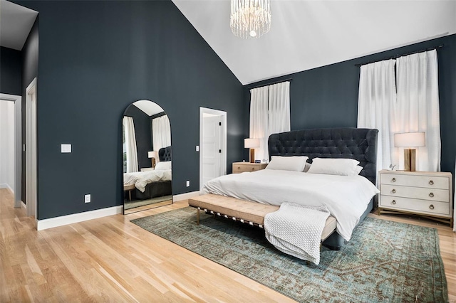 bedroom featuring arched walkways, baseboards, high vaulted ceiling, and wood finished floors