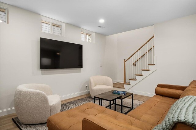 living area with baseboards, stairs, visible vents, and wood finished floors