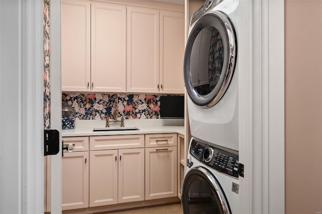laundry room featuring a sink, stacked washer and dryer, and cabinet space