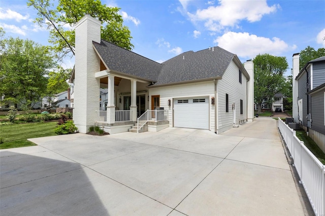 view of front of property with a chimney, driveway, an attached garage, a shingled roof, and a porch