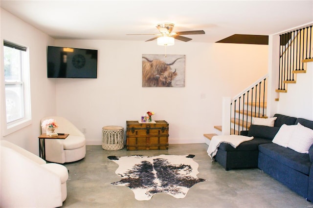 living room with concrete floors, stairway, baseboards, and a ceiling fan
