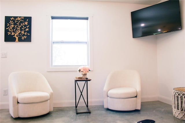sitting room featuring baseboards, plenty of natural light, and concrete floors