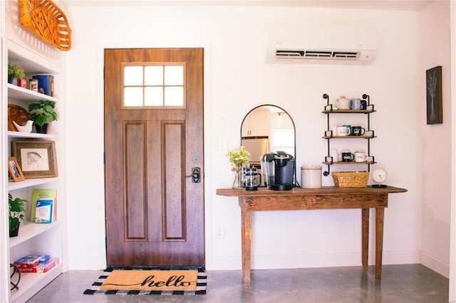 foyer entrance featuring finished concrete flooring, baseboards, and a wall unit AC