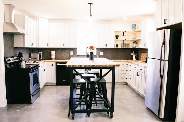 kitchen featuring wall chimney range hood, finished concrete floors, white cabinetry, backsplash, and appliances with stainless steel finishes