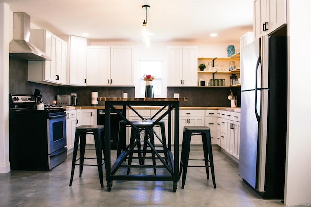 kitchen with concrete floors, white cabinets, wall chimney range hood, appliances with stainless steel finishes, and tasteful backsplash