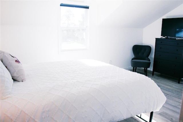 bedroom with vaulted ceiling and wood finished floors