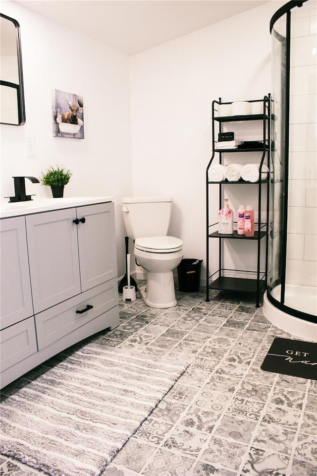 bathroom featuring vanity, toilet, baseboards, and a stall shower