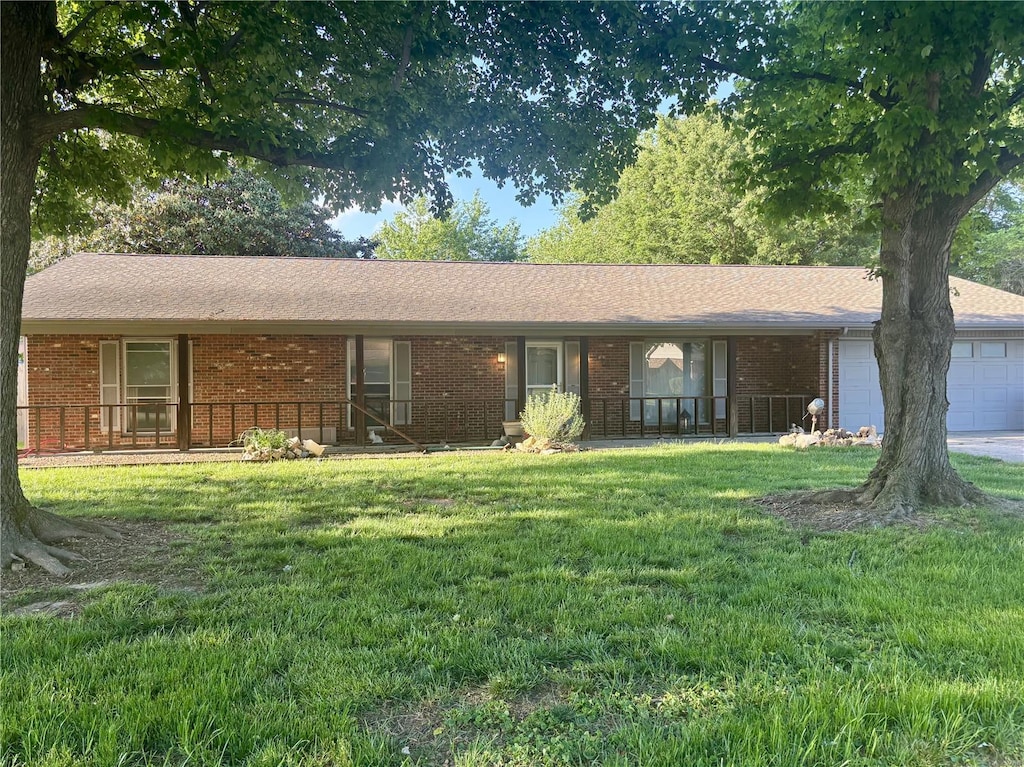 single story home with a porch, an attached garage, a front lawn, and brick siding