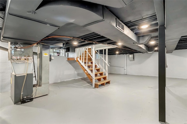 below grade area featuring stairs, heating unit, and visible vents