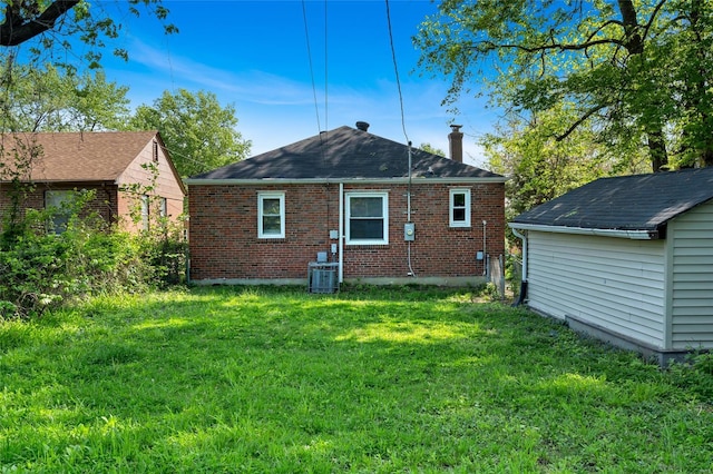 back of property with central air condition unit, brick siding, and a lawn