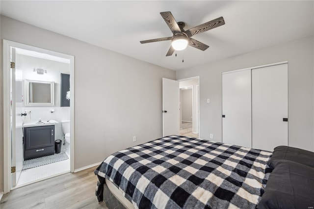 bedroom with ceiling fan, ensuite bath, light wood finished floors, and a closet