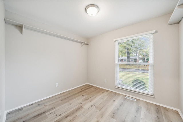 empty room with baseboards, visible vents, and wood finished floors