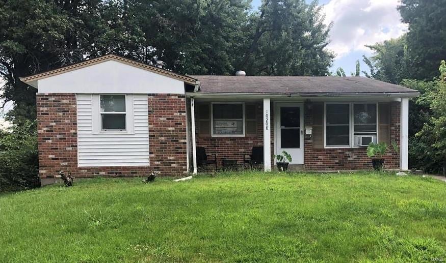 view of front of home featuring brick siding, a front yard, and a porch